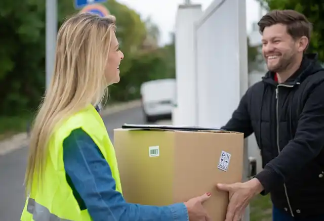 Entregadora com colete refletivo entregando uma caixa a um cliente sorridente